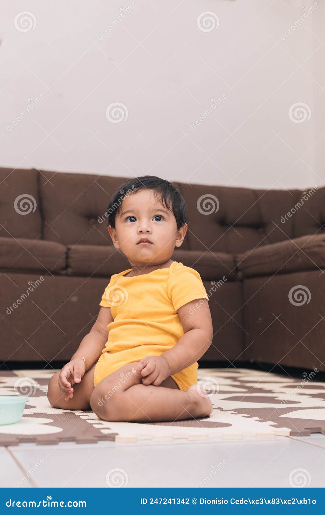 baby kneeling in the living room of the house watching