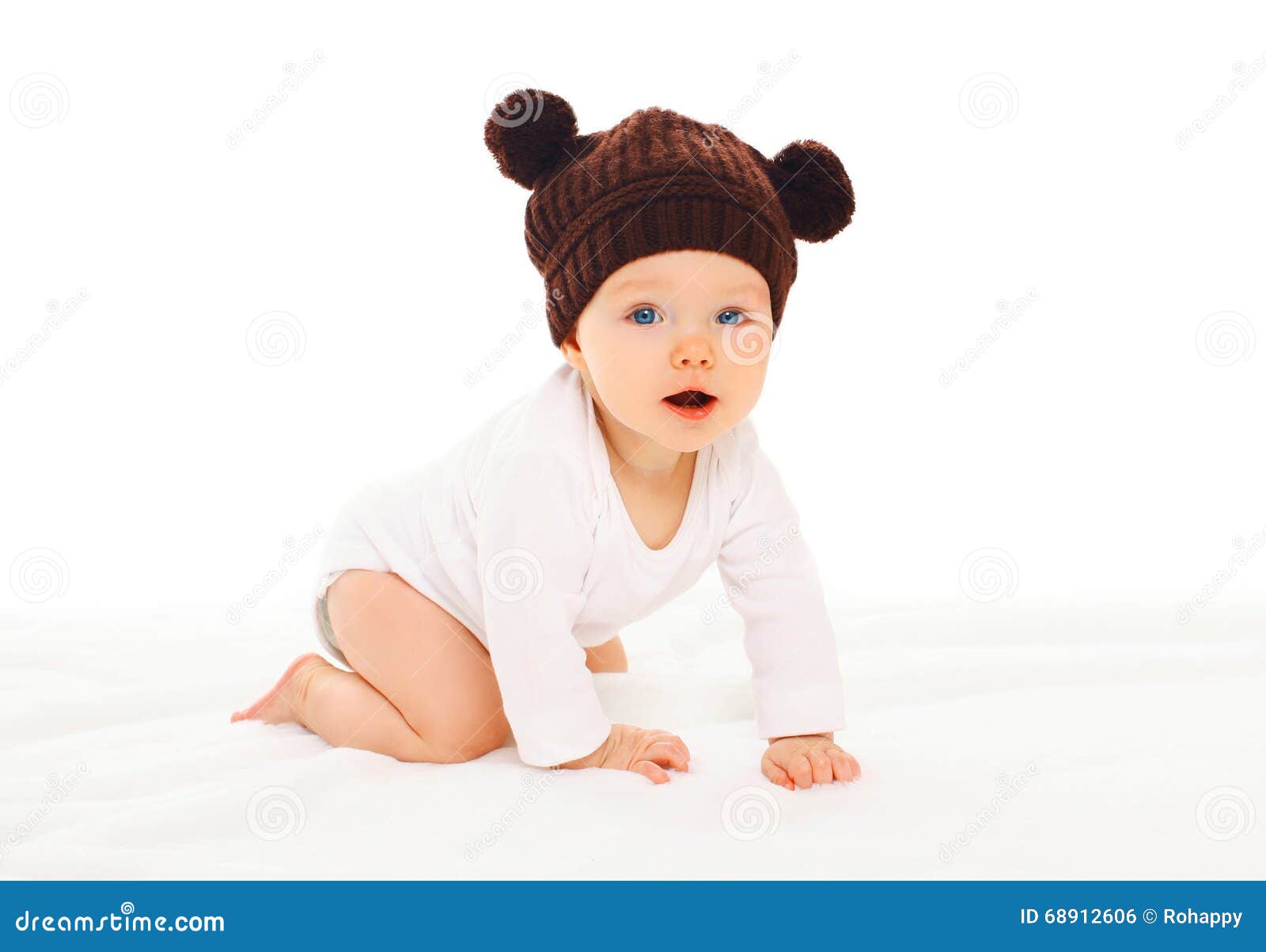 Baby in Knitted Brown Hat with Ears Bears Crawls on White Stock Photo