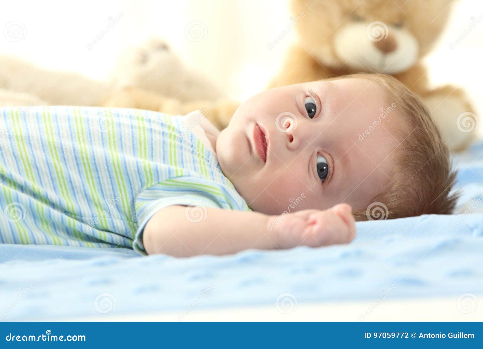 Baby Lying on a Bed and Looking at You Stock Photo Image of face