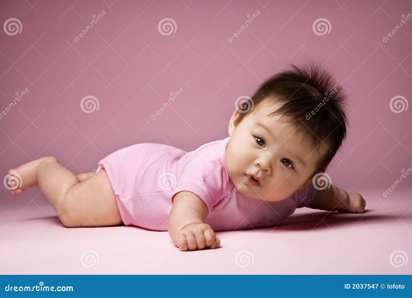 baby lying on stomach looking at viewer.