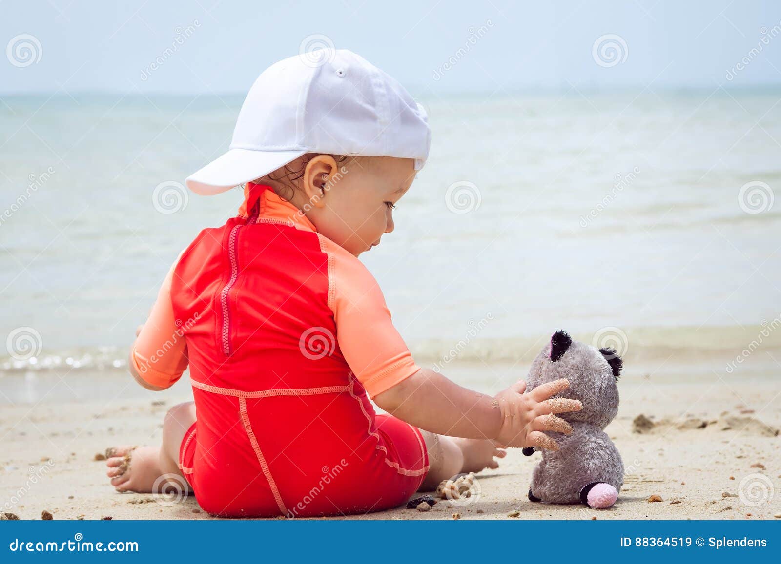 Child playing with toy on beach with sea on background. Concept for friendship and happy childhood