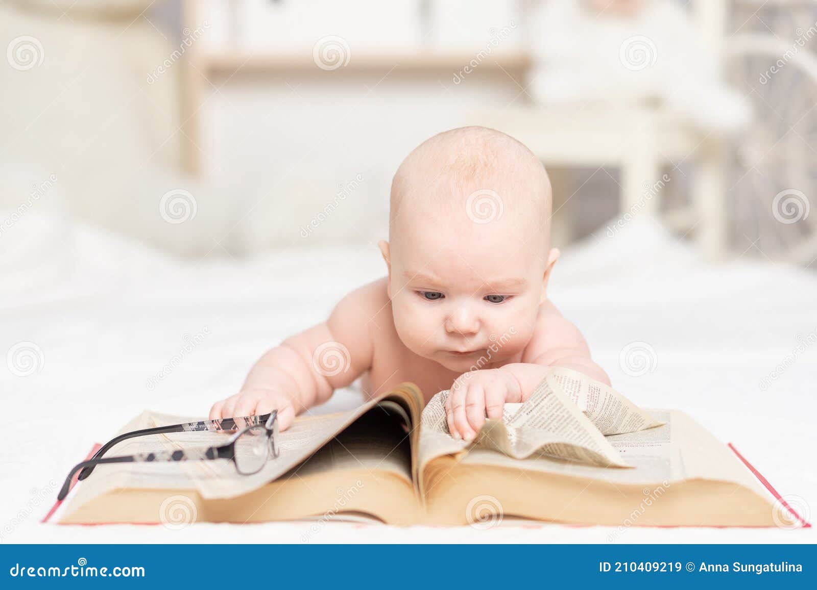 Baby Reading a Book or Looking at it in the Nursery, Learning and