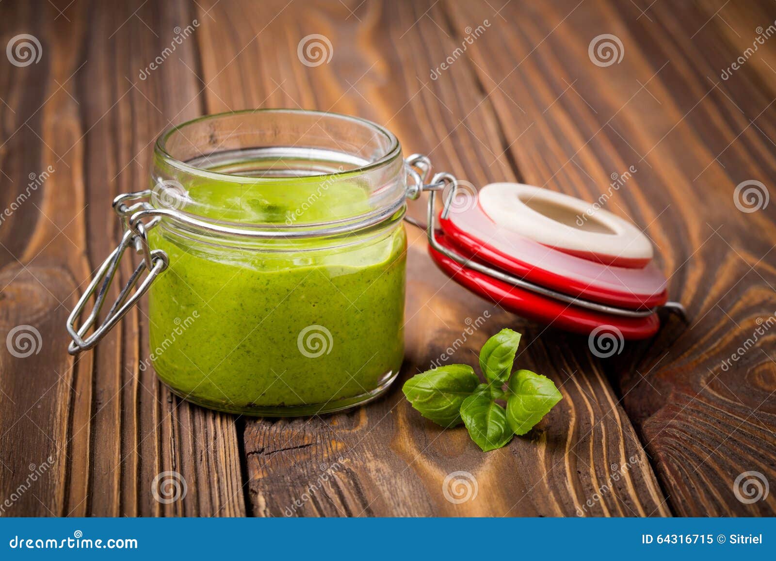 Baby-Spinat Pesto Diy selbst gemachter. Natürlicher selbst gemachter gesunder grüner Pesto DIY-strengen Vegetariers sehr gemacht von den Baby Spinats- und pininüssen in einem Glasgefäß auf einem Holztisch