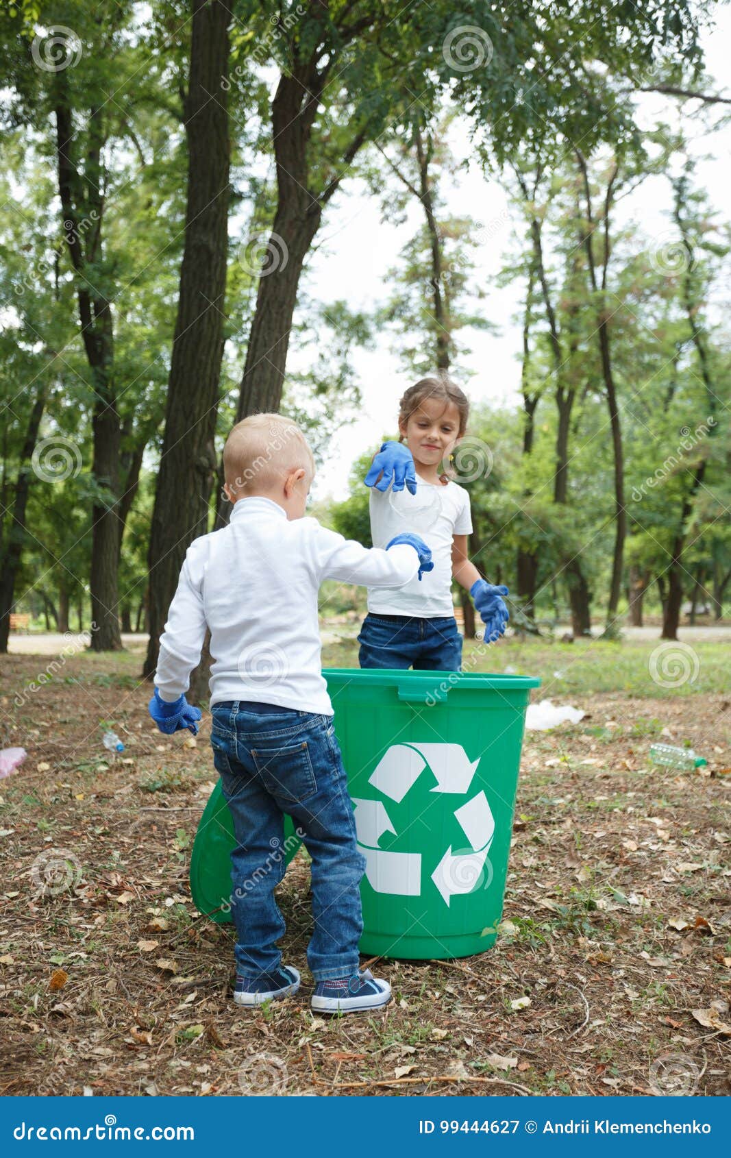 back of fair boy with hairstyle pigtails. throwing plastic bag into recycling bin. land and rubbish on the background.