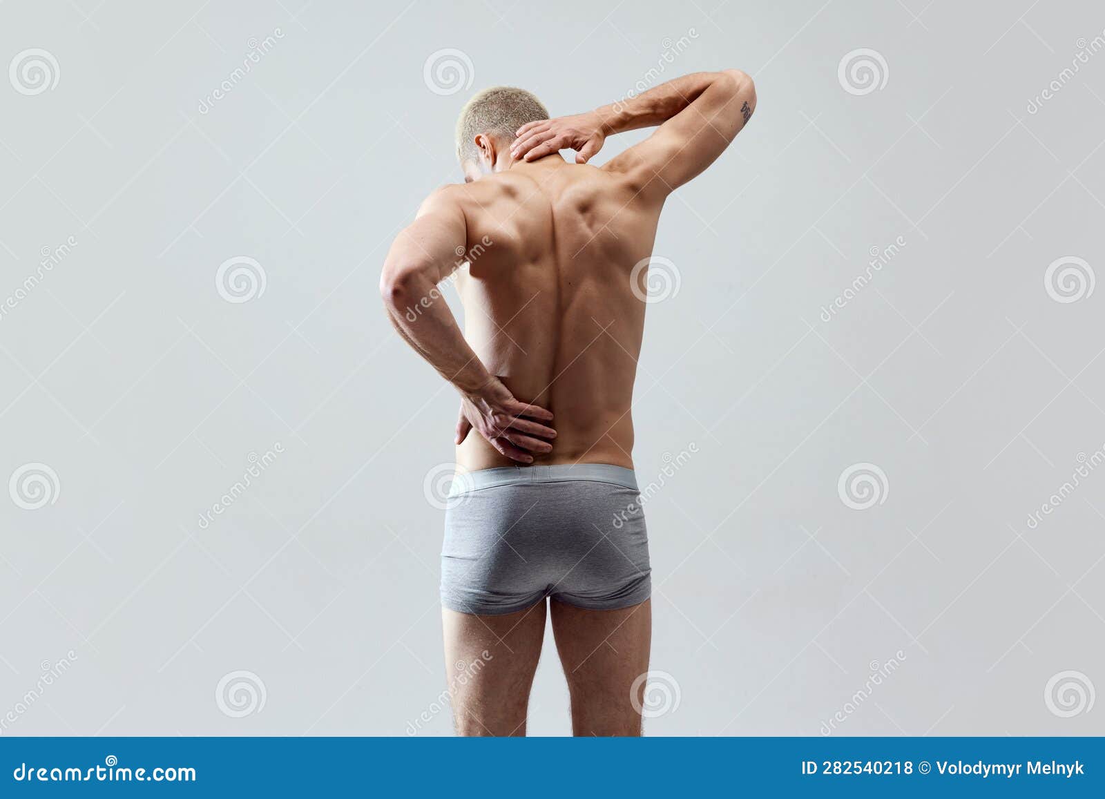 Beautiful strong muscular young man standing in his underwear with a naked  torso behind him red background Stock Photo