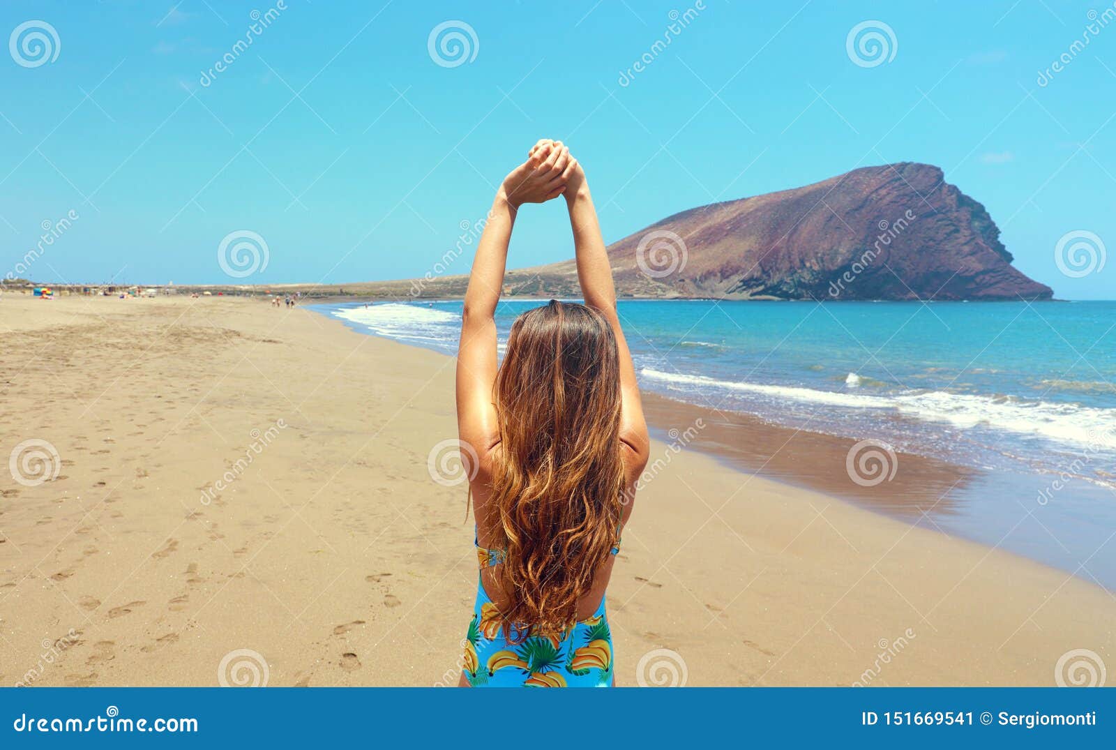 back view beautiful woman doing stretching exercises on the beach in playa la tejita, tenerife