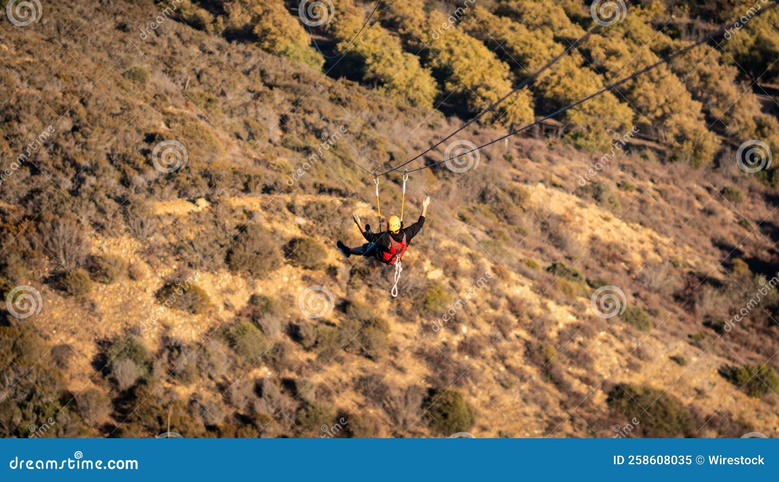 Back View of Human Flying with Zipline Over Greenery Mountains Stock