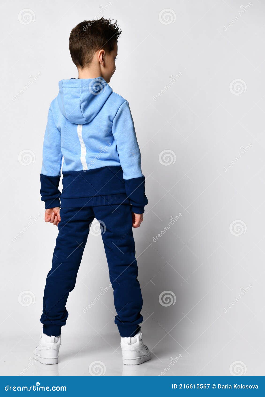 Kid in Warm Overalls, White Sneakers Walking Along the Studio Wall ...