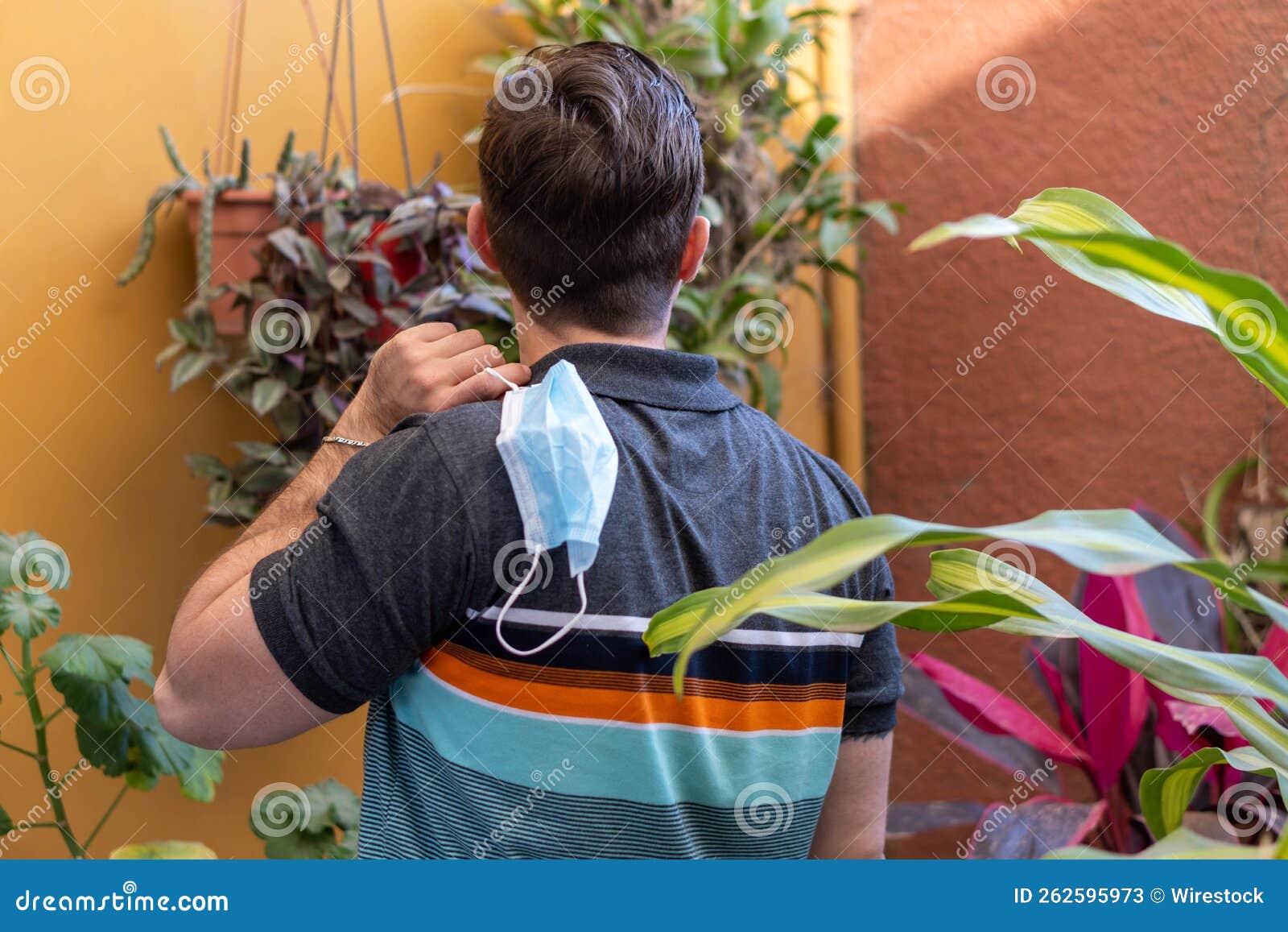 Back View of a Male Holding a Protective Face Mask Behind His Back