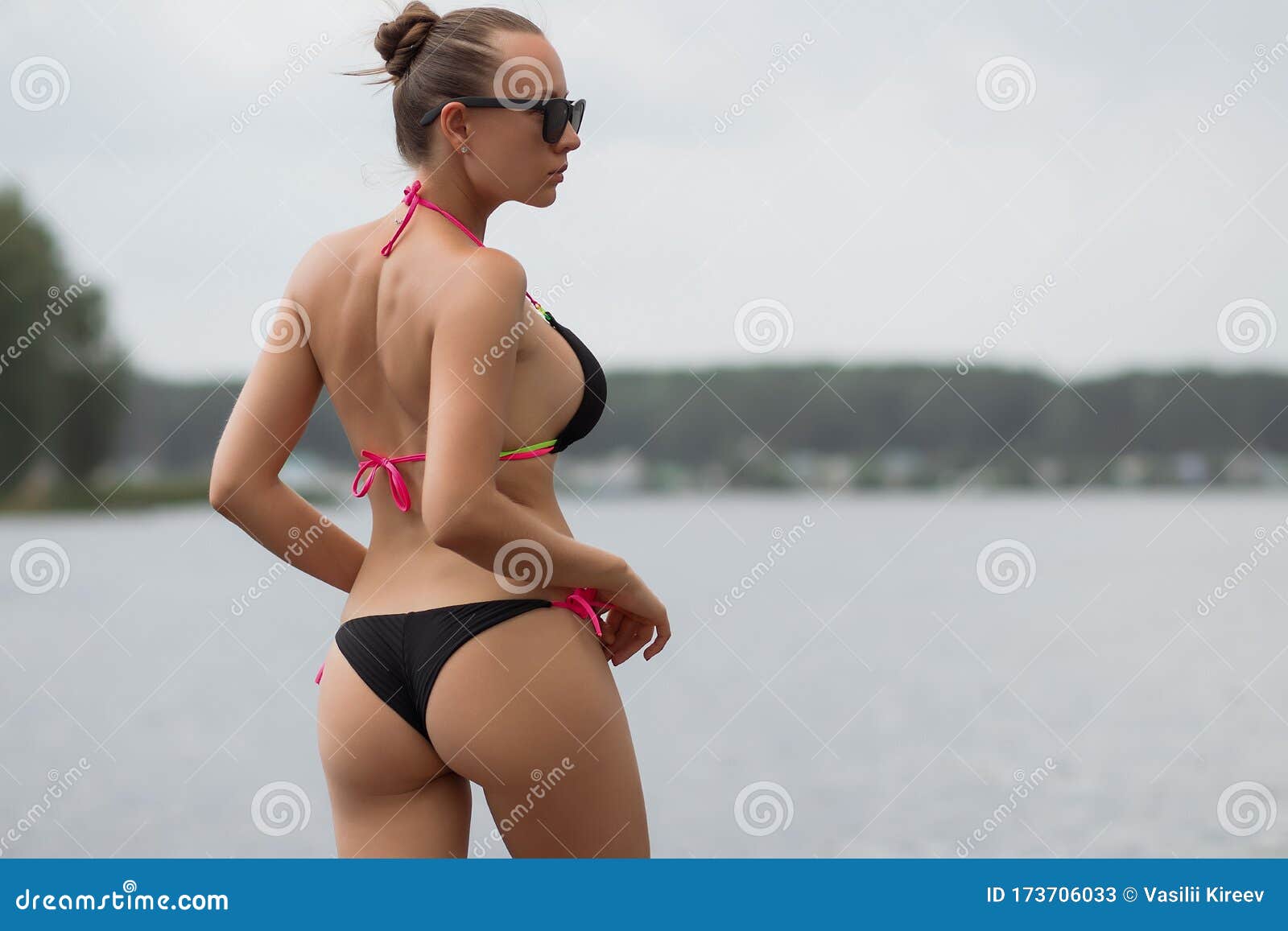 Back view of slim woman in sunglasses taking off swimsuit panties on backgr...