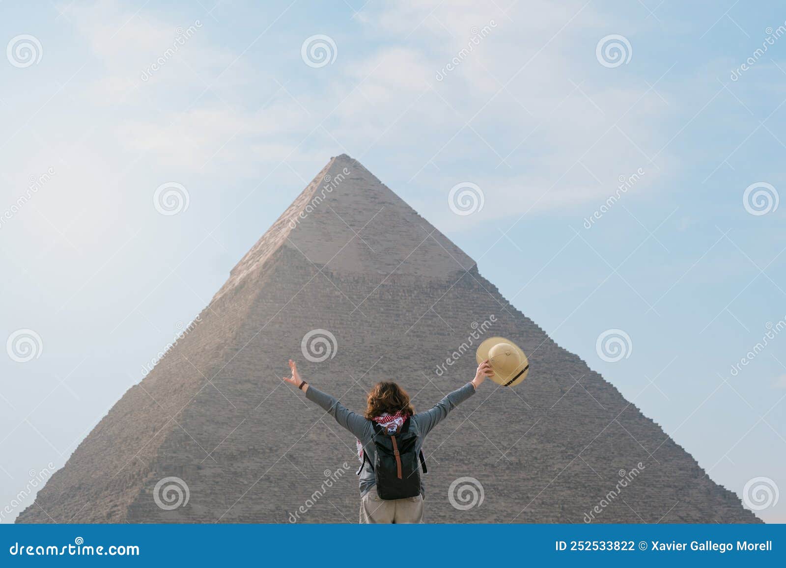back view of tourist woman standing in front of a pyramid. egypt, cairo - giza