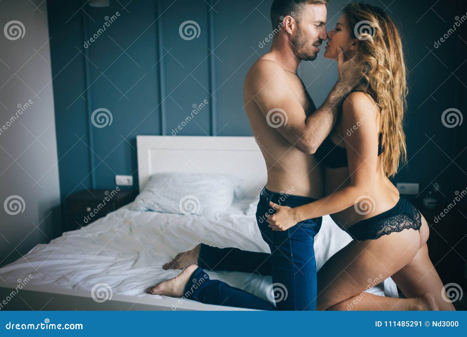Back View of Woman in Black Panties Holding Her Bra while Man is Lying on Bed Stock Image pic pic