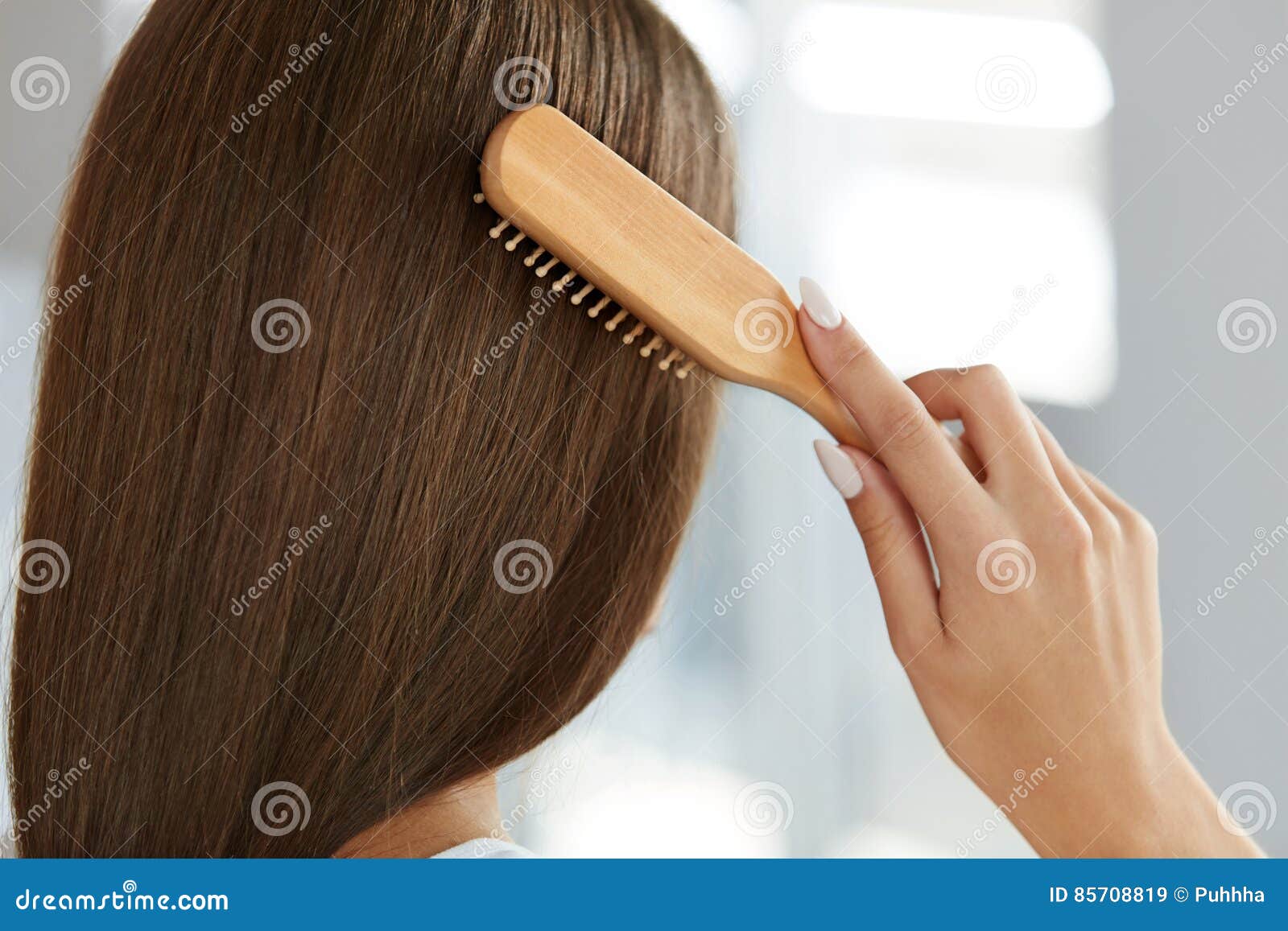 back view of woman with healthy long hair brushing it with brush