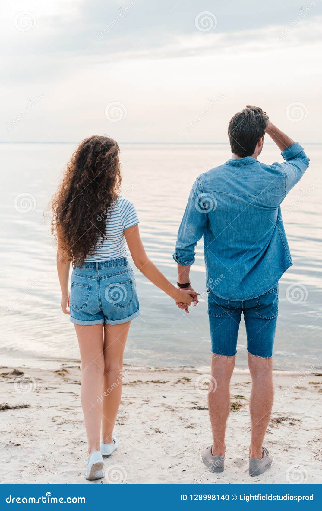 Back View of Young Couple Holding Hands and Looking Stock Photo Image