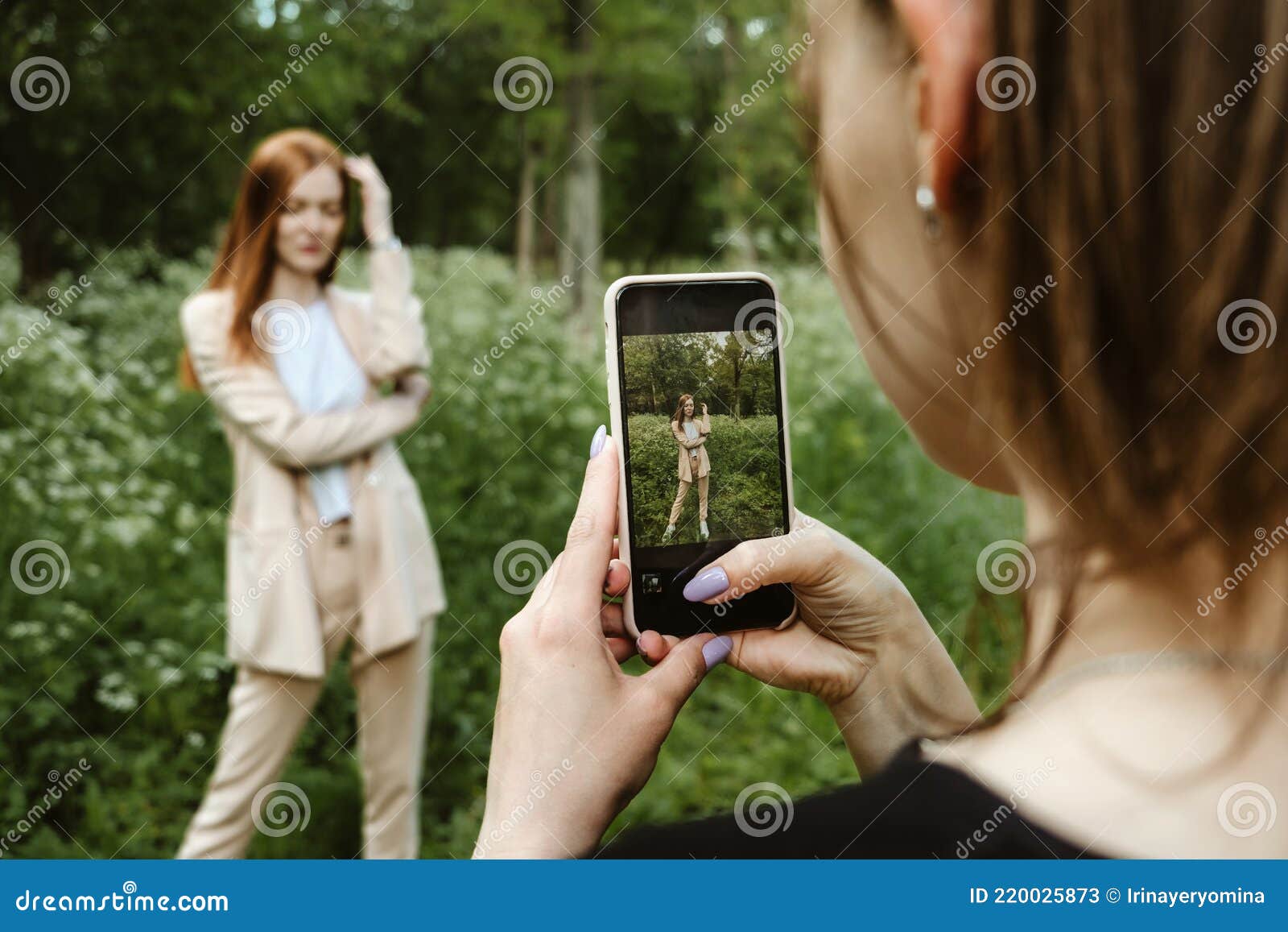 Back View Of Young Woman Holding Cell Phone And Making Photo Of Her