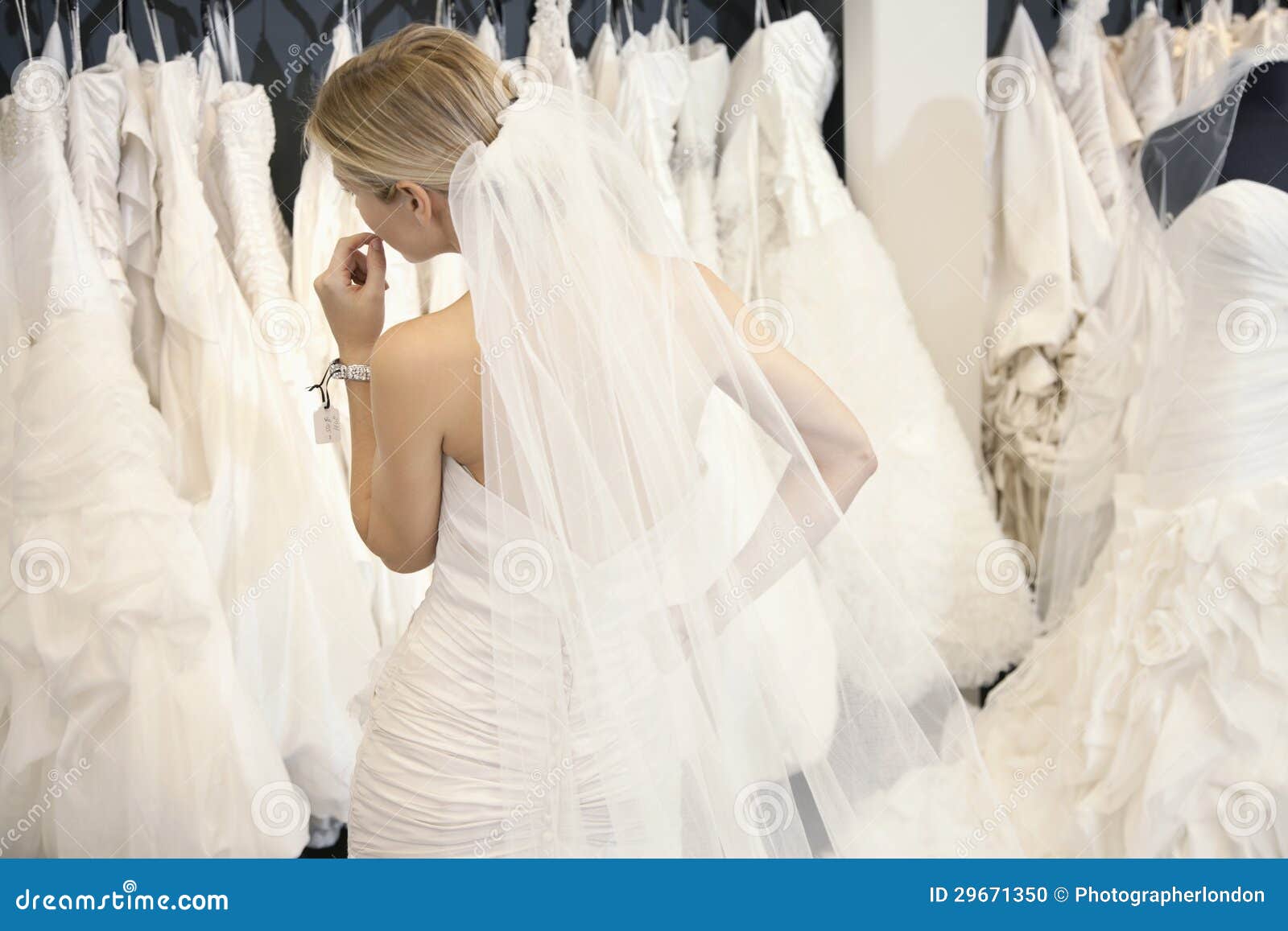 back view of a young woman in wedding dress looking at bridal gowns on display in boutique