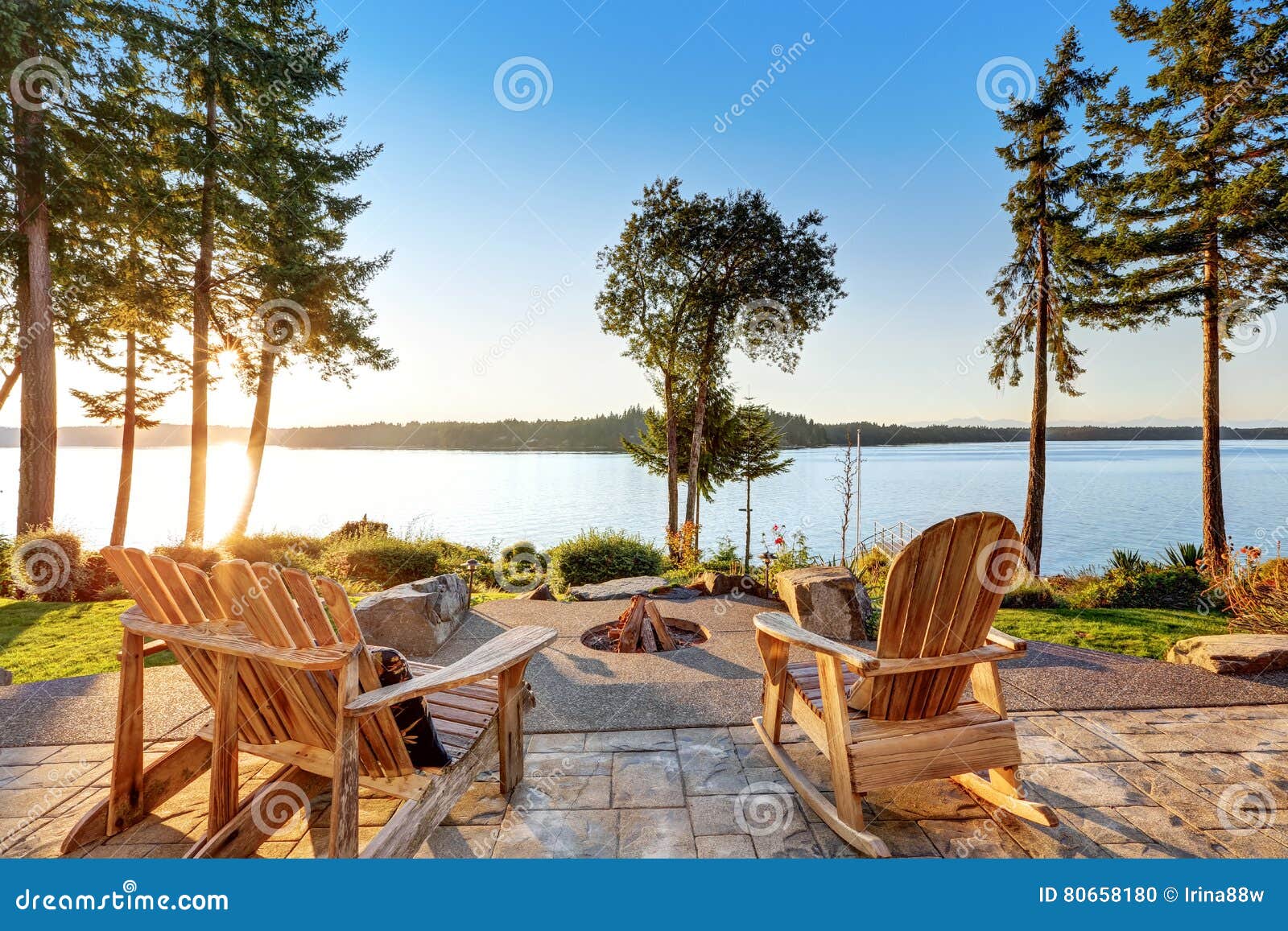 back yard of waterfront house with adirondack chairs and fire pit