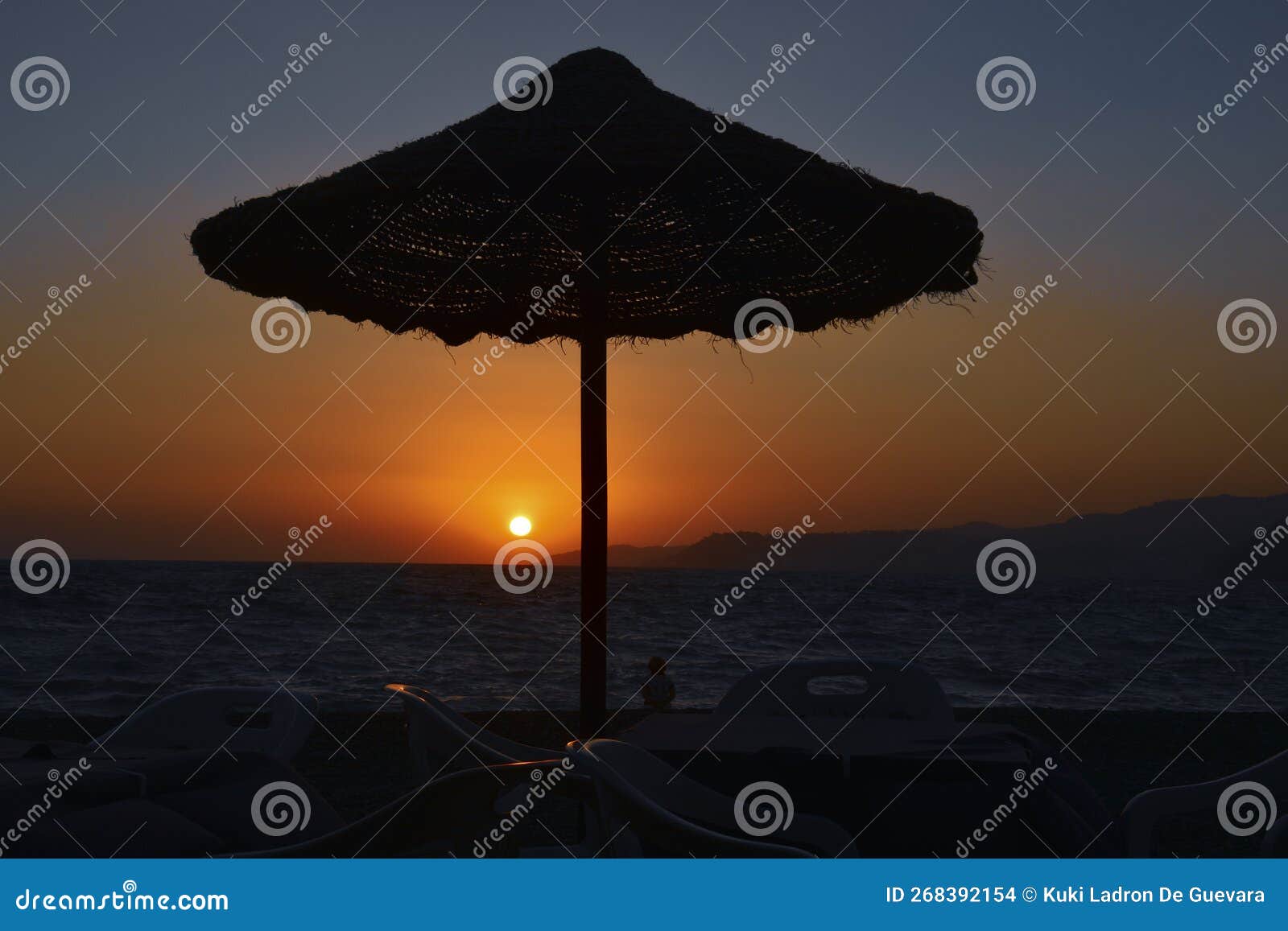 beach umbrella at sunset with setting sun