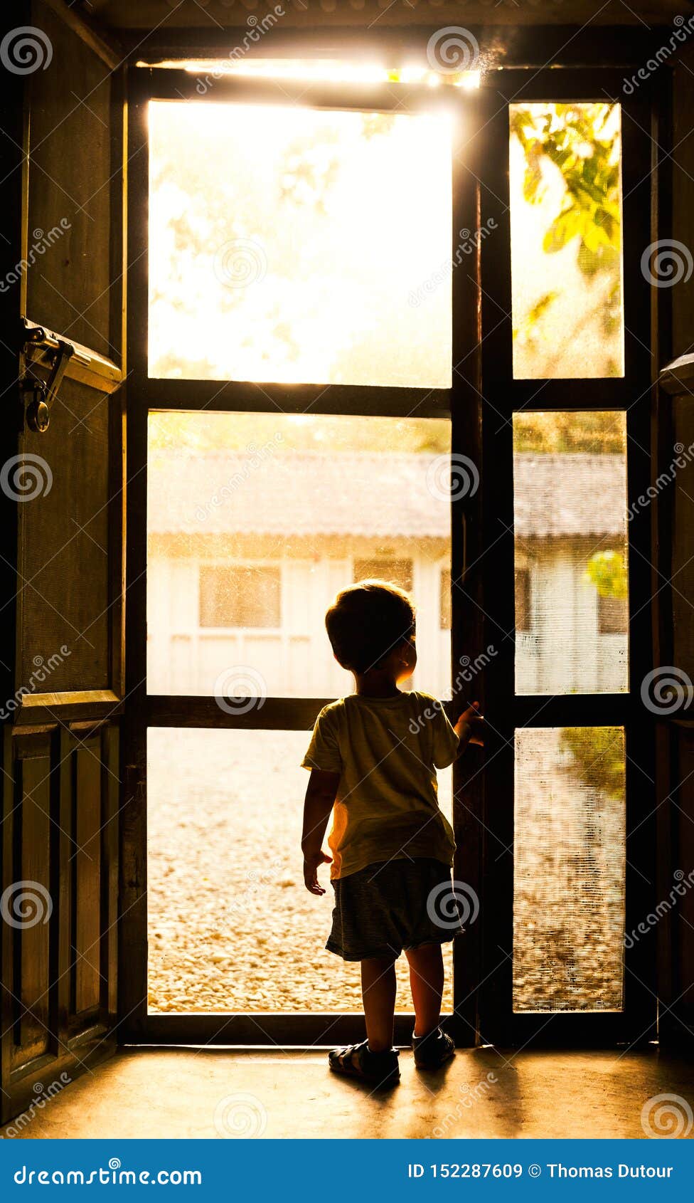Backlit Toddler Standing In Front Of Door Stock Image