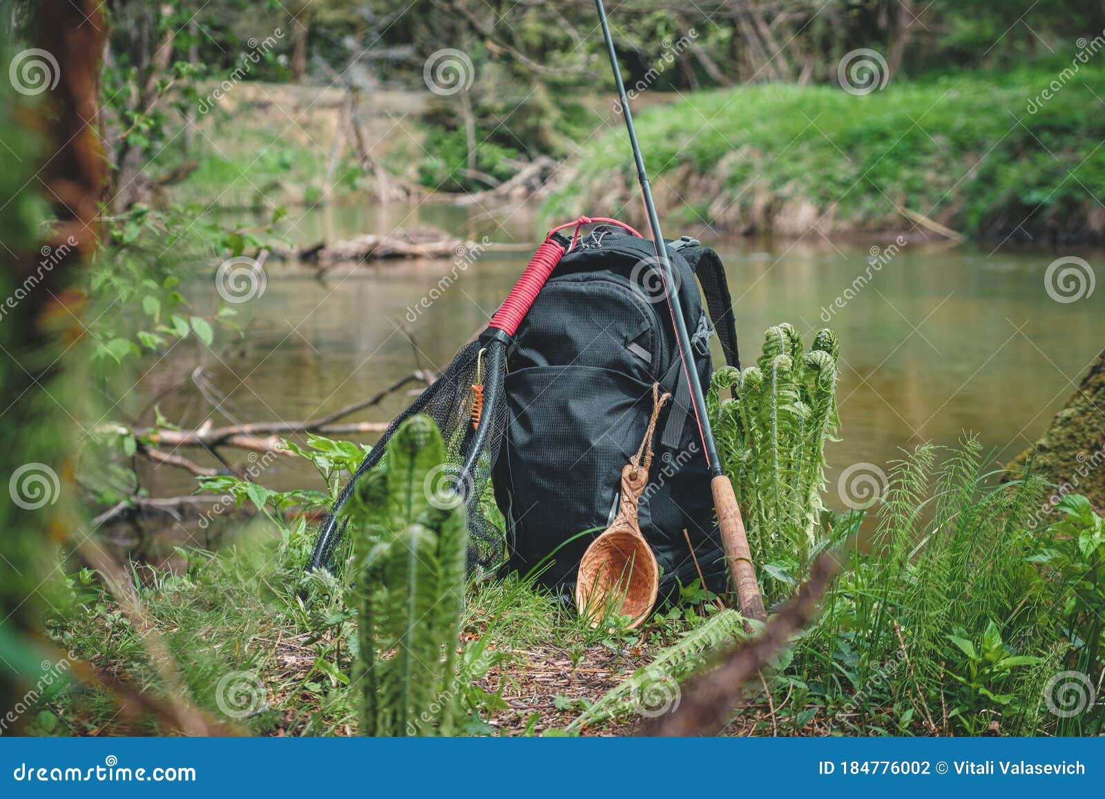 Backpack and Fishing Rod on the River. Fishing Gear Stock Photo