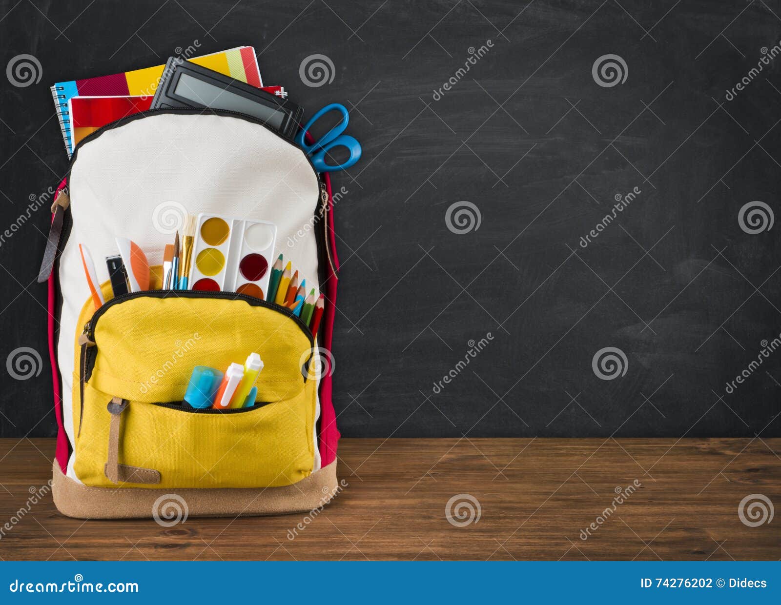 Backpack Full of School Supplies Over Black School Board Background