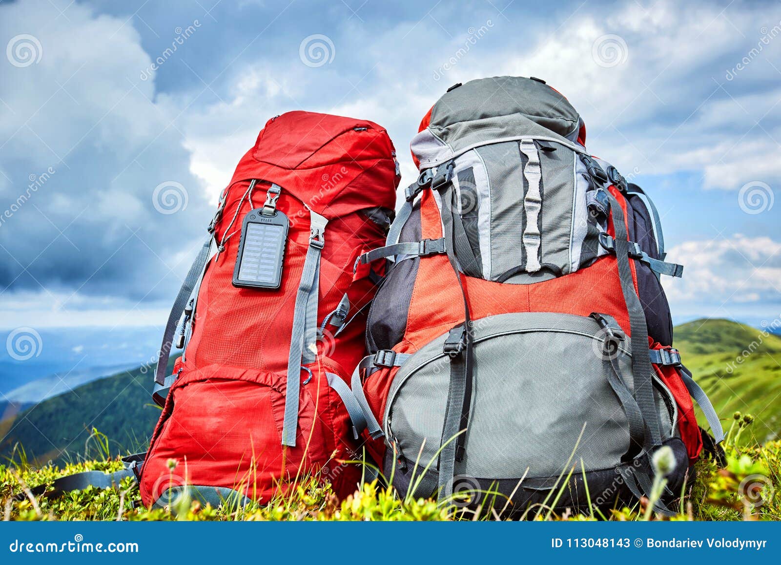 Backpacks in the Mountains Overlooking the Mountains on the Green Grass