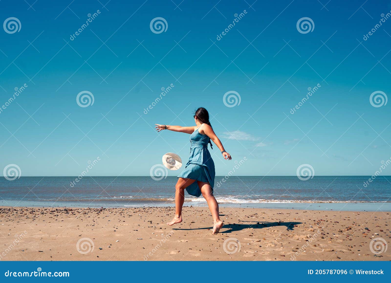 Backshot of a Young Female in a Summer Dress Cathing Up the Hat on the ...