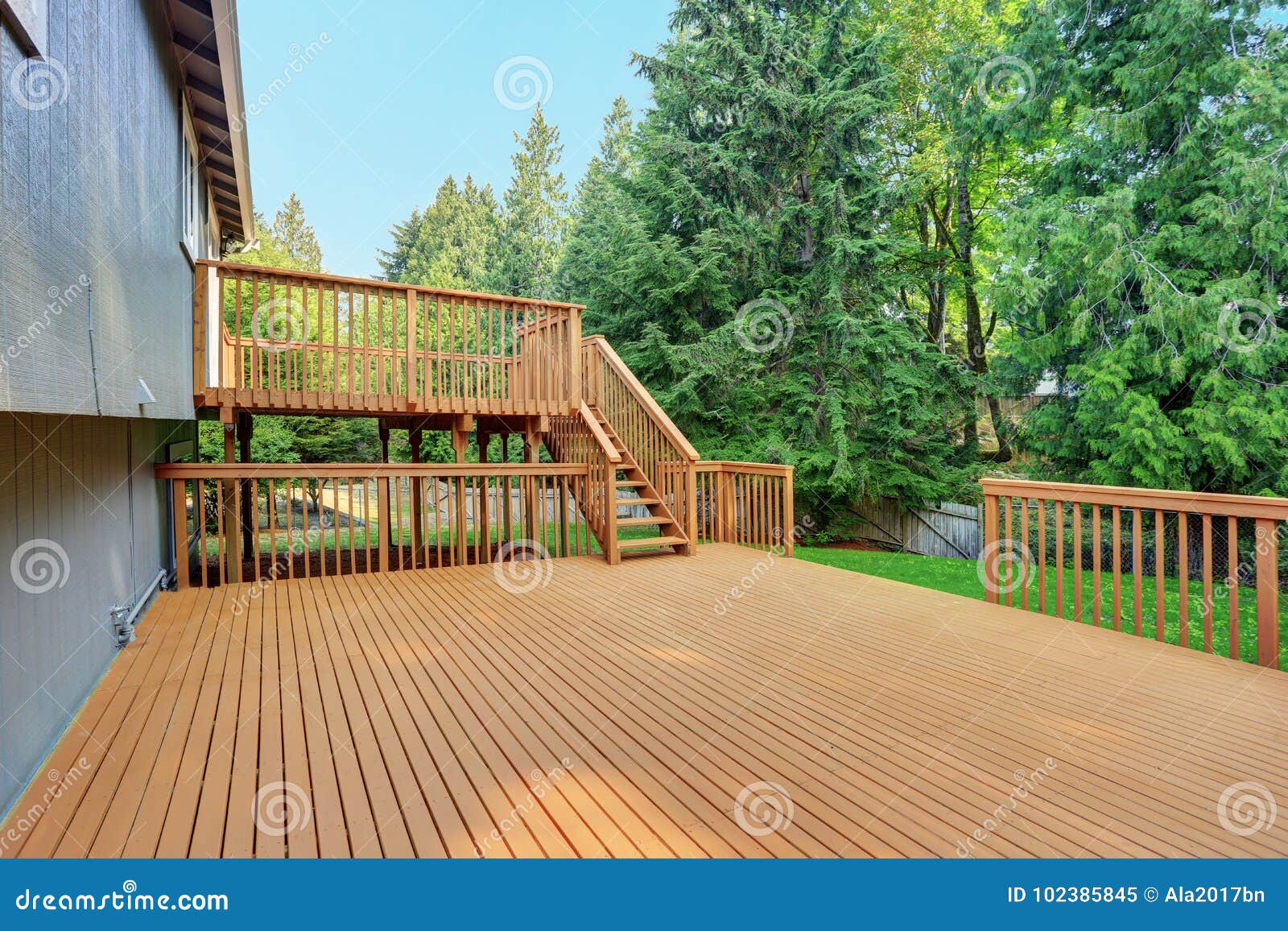 backyard view of grey rambler house with upper and lower decks