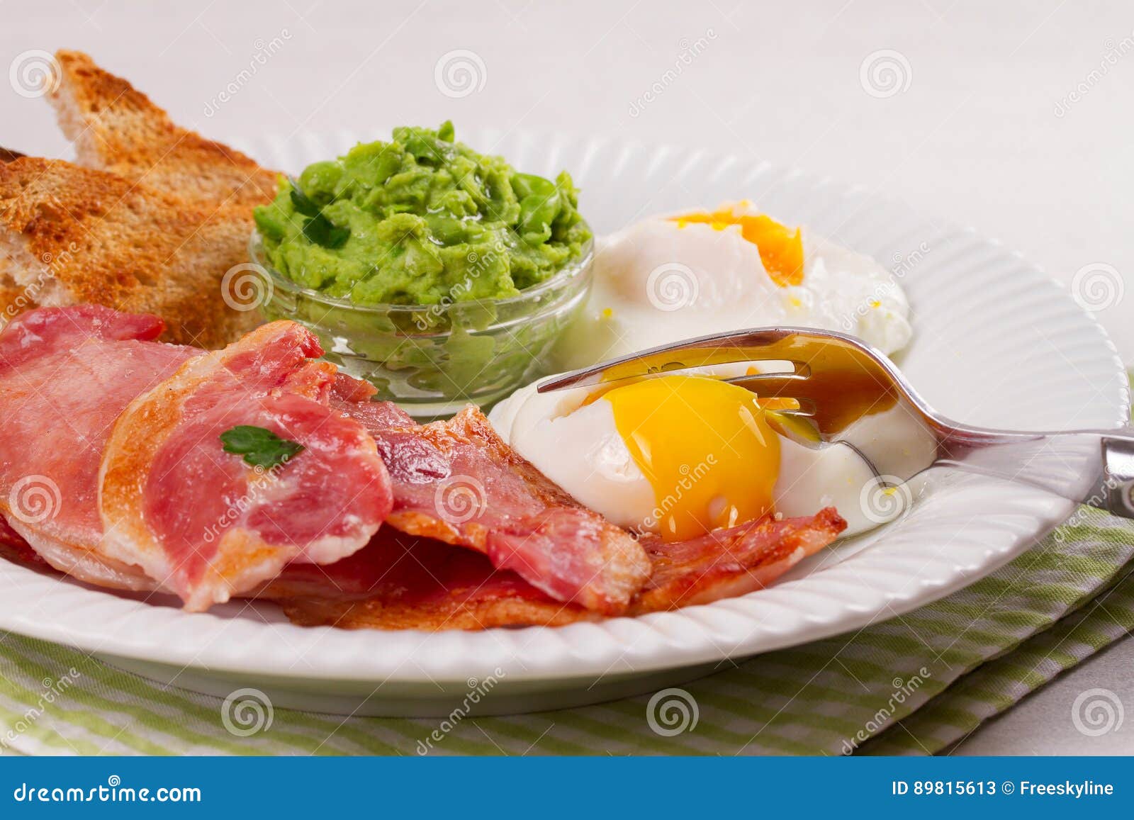 Bacon, Poached Eggs, Mashed Peas and Toasts on White Plate. Grilled