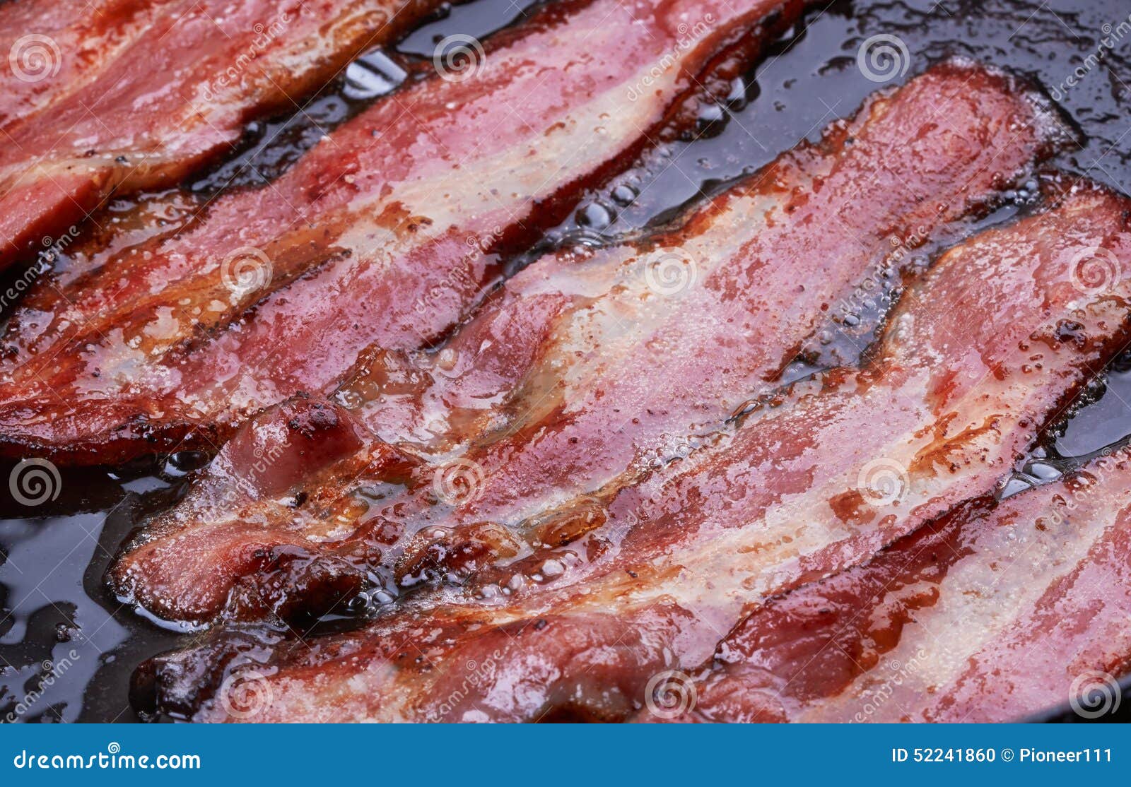 Bacon strips or rashers being cooked in frying pan