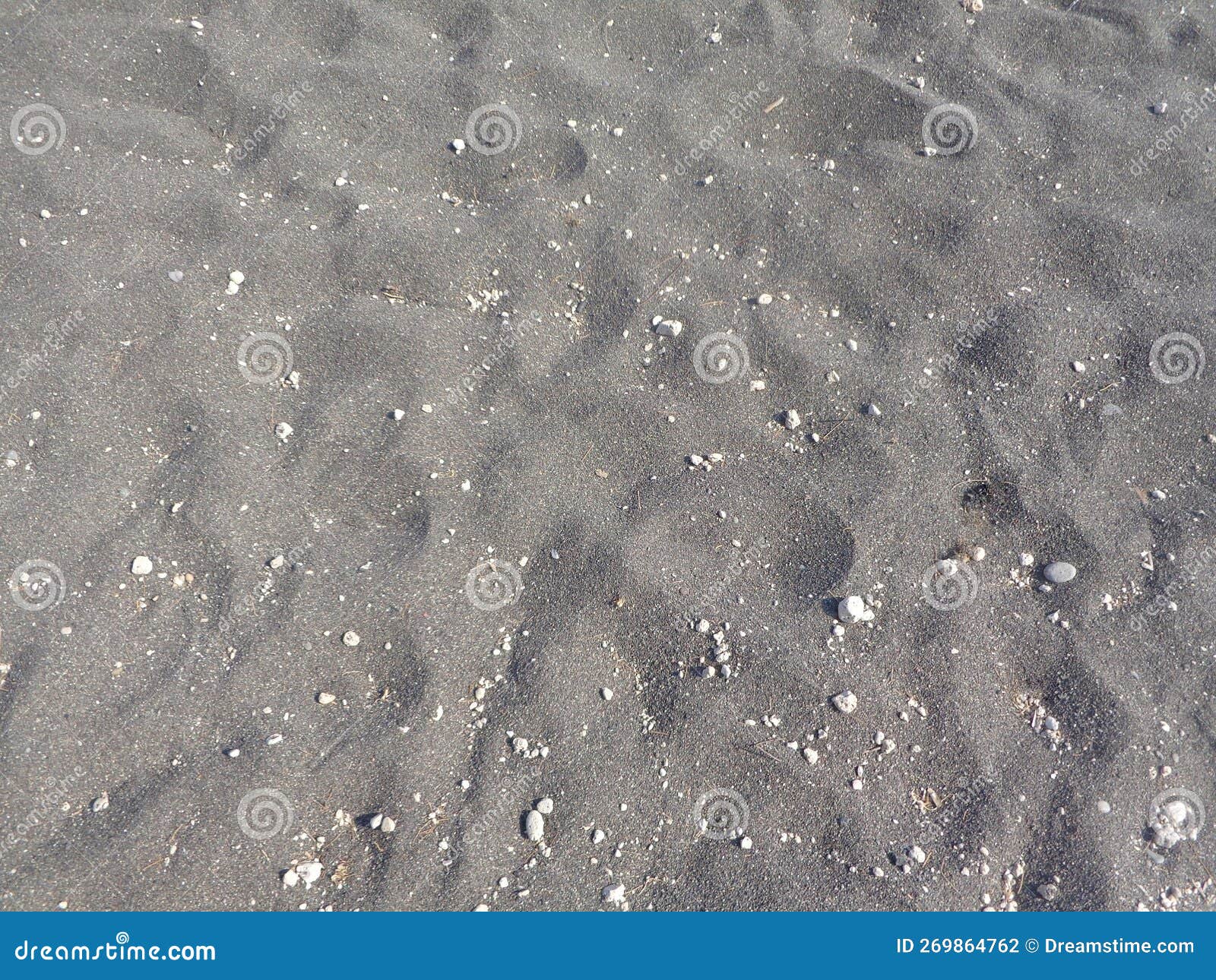Bakckground of Black Sand Footprints with Little Rocks Stock Photo