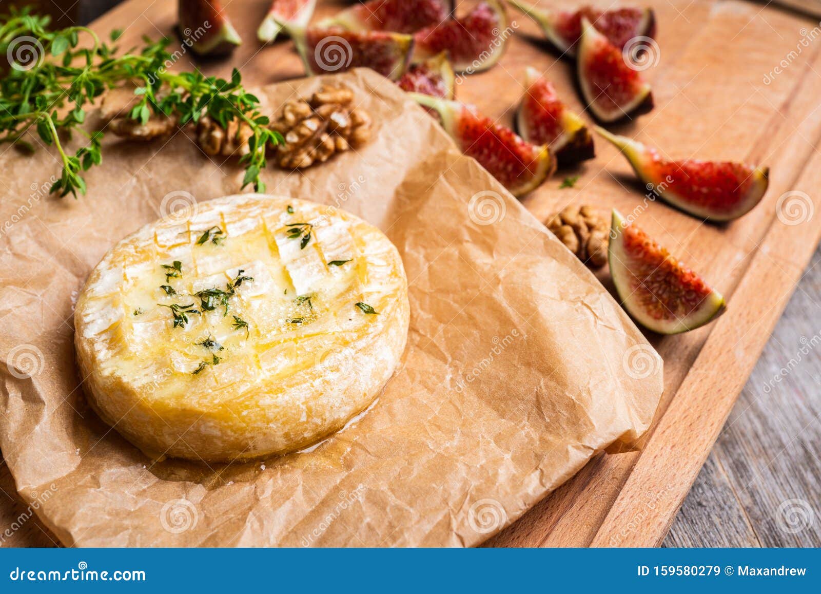 baked camembert cheese with figs, walnuts, honey and thyme on the rustc background
