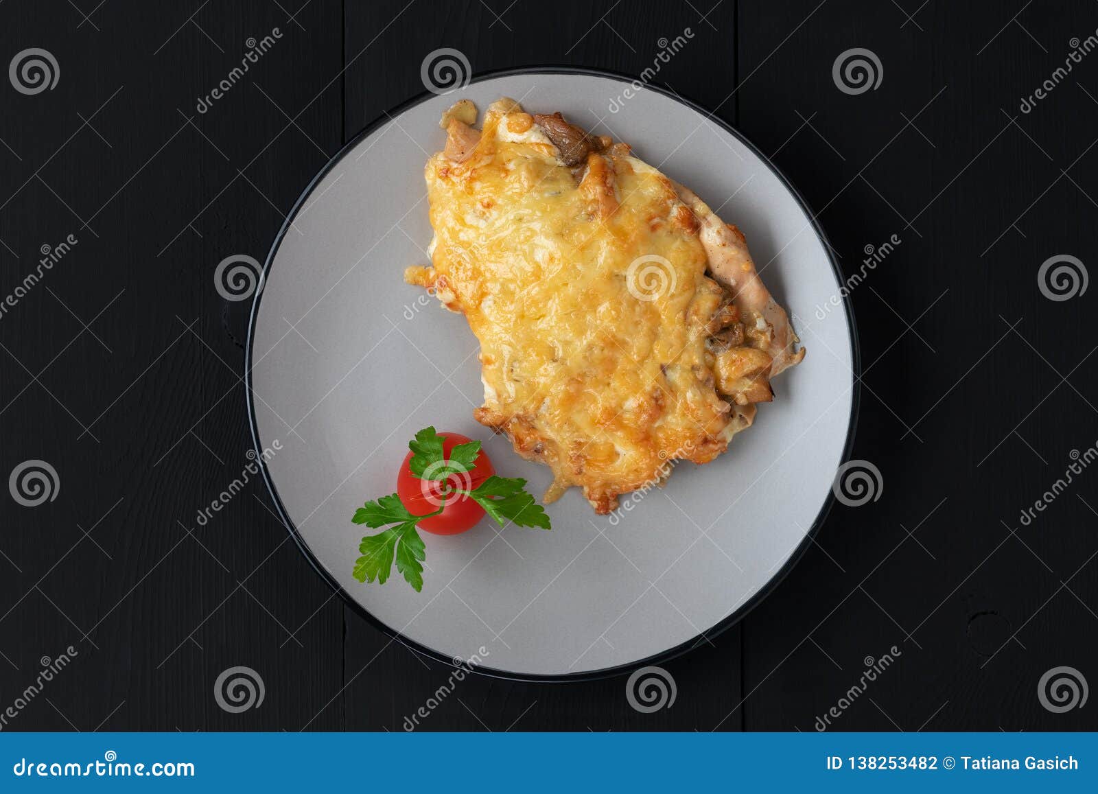 baked chicken under cheese with tomate and parsley