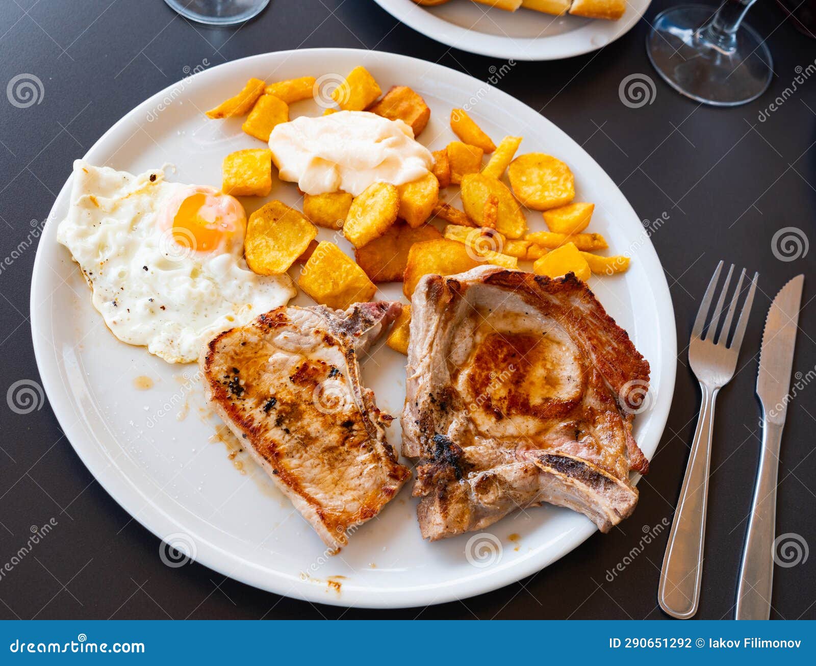 Baked Pork Chop with Side Dish of Potatoes, Fried Egg and Aioli Stock