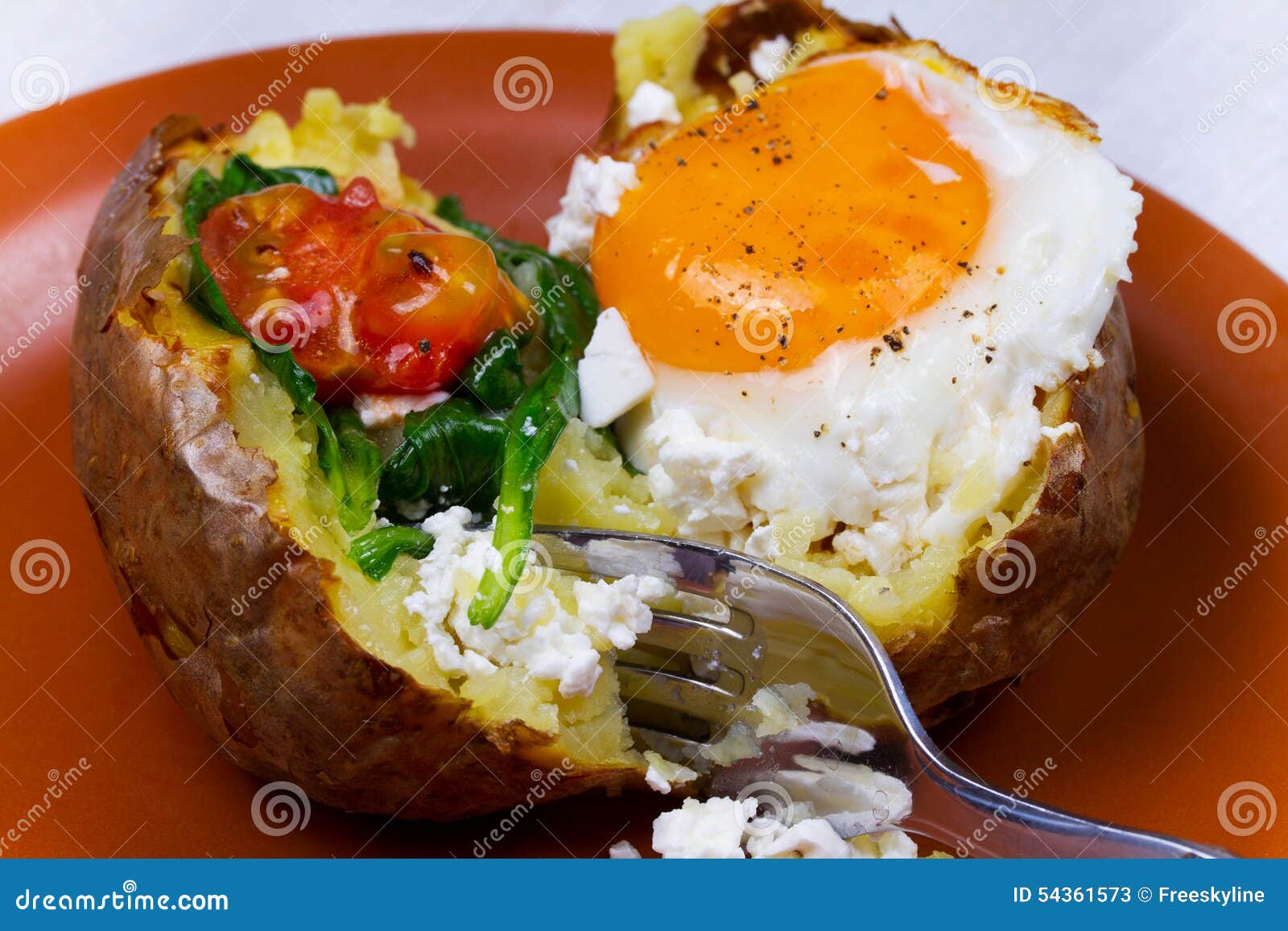 Baked Potato with Fried Egg, Feta, Spinach and Tomato Cherry. Stock