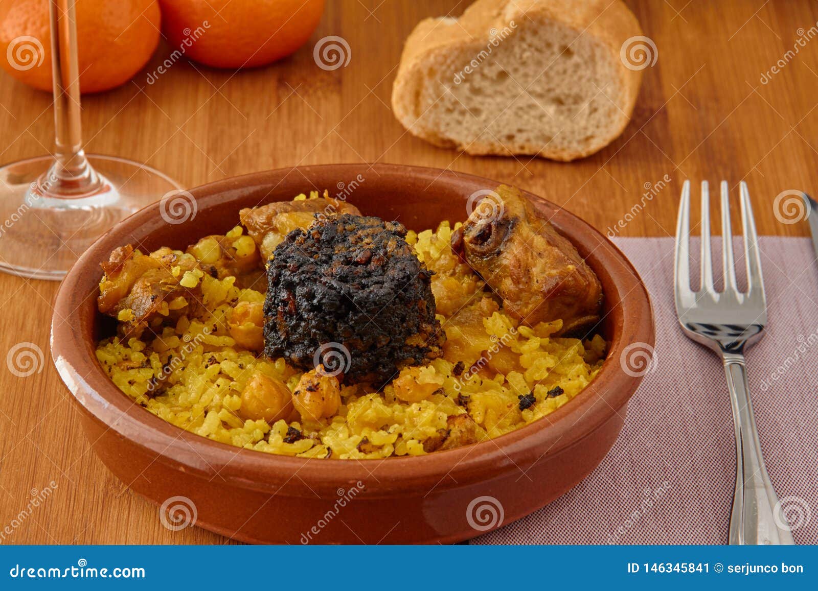 baked rice in a pottery dish accompanied by pork, chickpeas, blood sausage, tomato and garlic. traditional