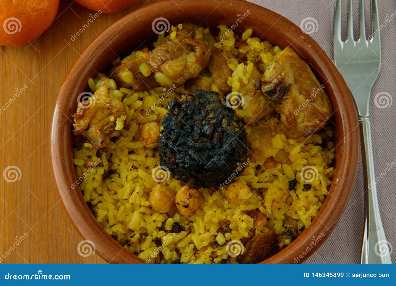 baked rice in a pottery dish accompanied by pork, chickpeas, blood sausage, tomato and garlic. traditional