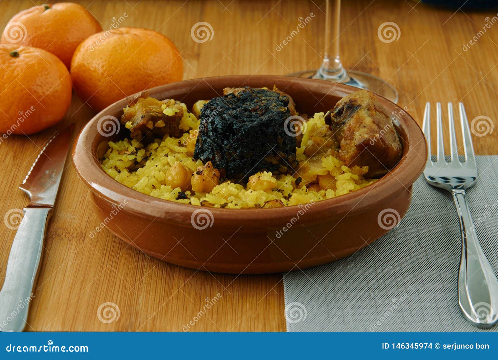 baked rice in a pottery dish accompanied by pork, chickpeas, blood sausage, tomato and garlic. traditional