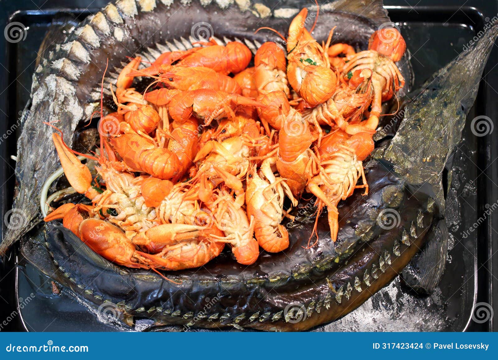 baked sturgeons and crayfish on a black pan,
