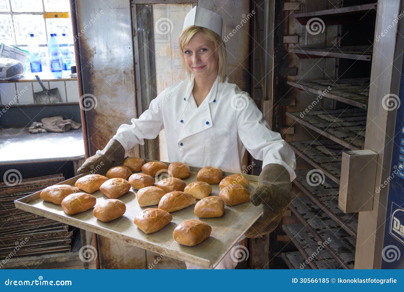 Baker in Bakehouse or Bakery Putting Bread in the Oven Stock Image