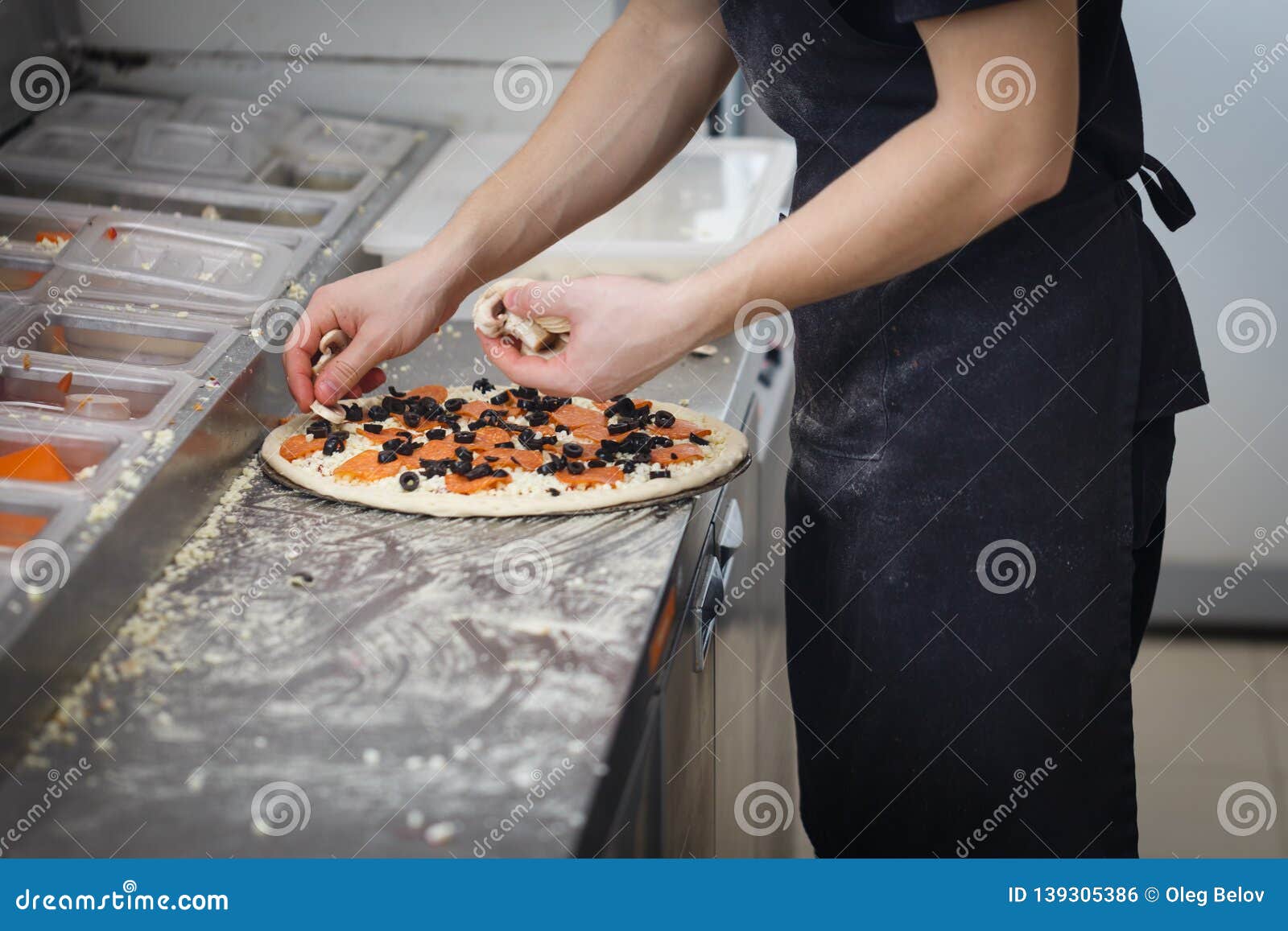 Baker Lays the Stuffing on the Pizza in the Fast Food Restaurant Stock