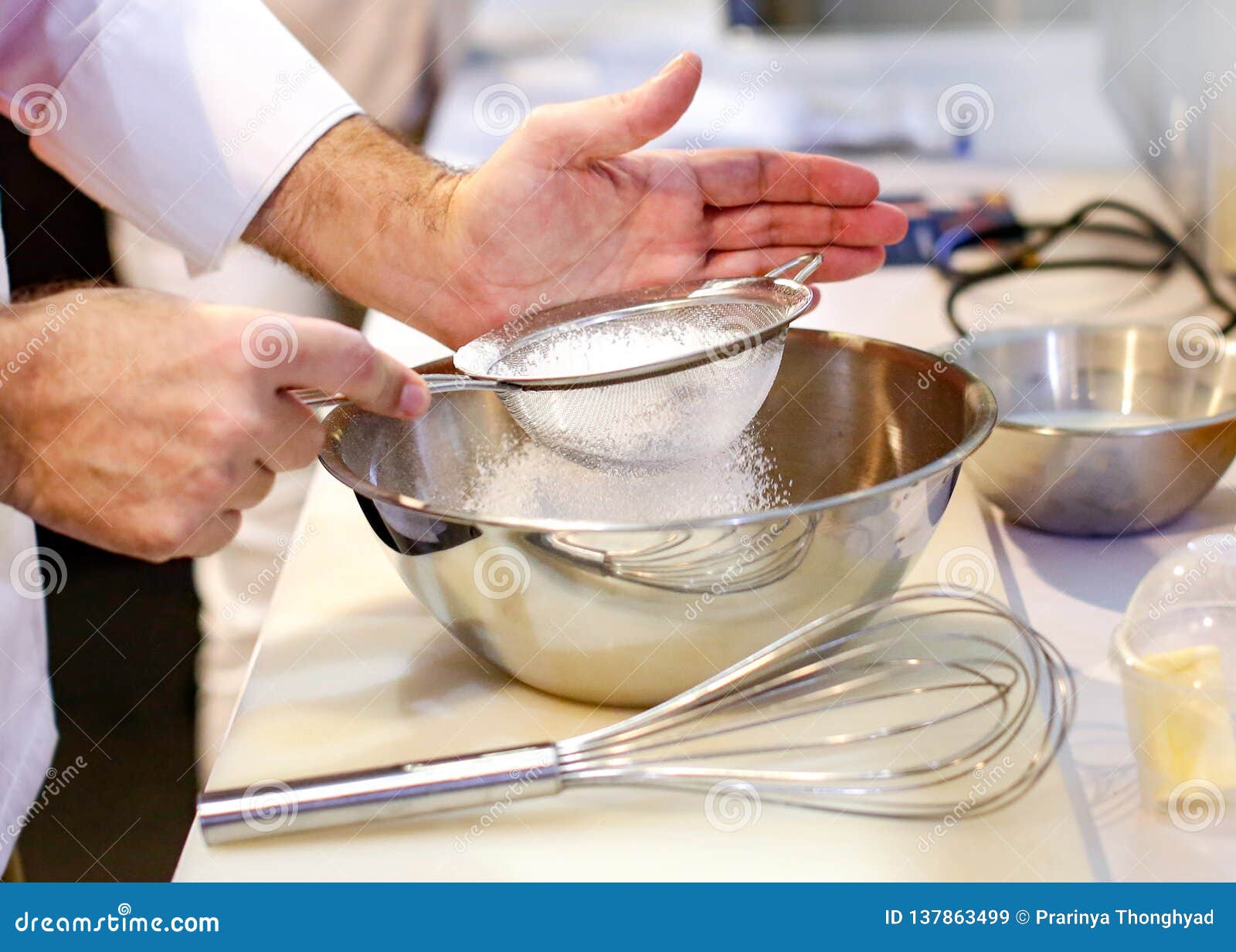 Baker Sieving Flour into a Bowl in the Kitchen of the Bakery Stock