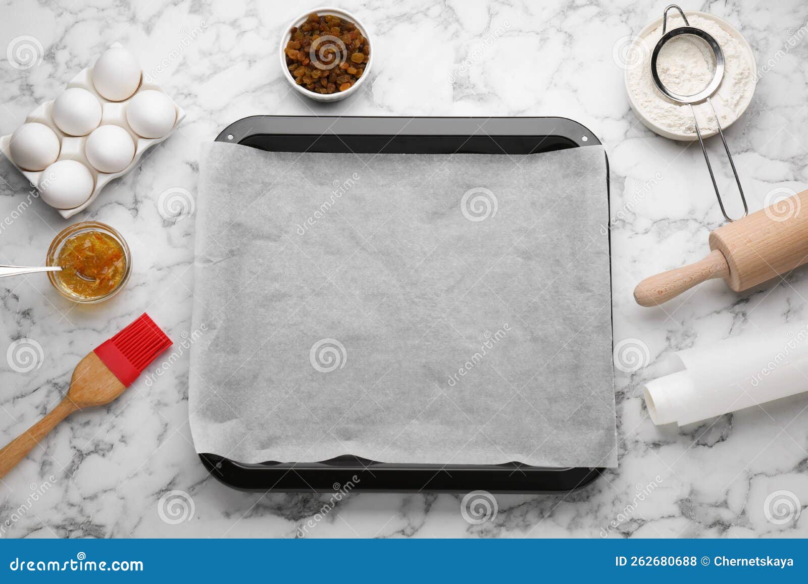 Baking Pan with Parchment Paper and Ingredients on White Marble Table