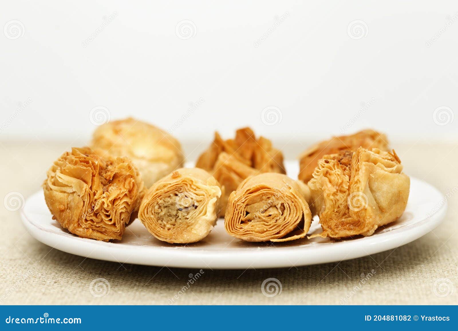 baklava made of thin dough with chopped nuts and honey syrup on the table on a light background