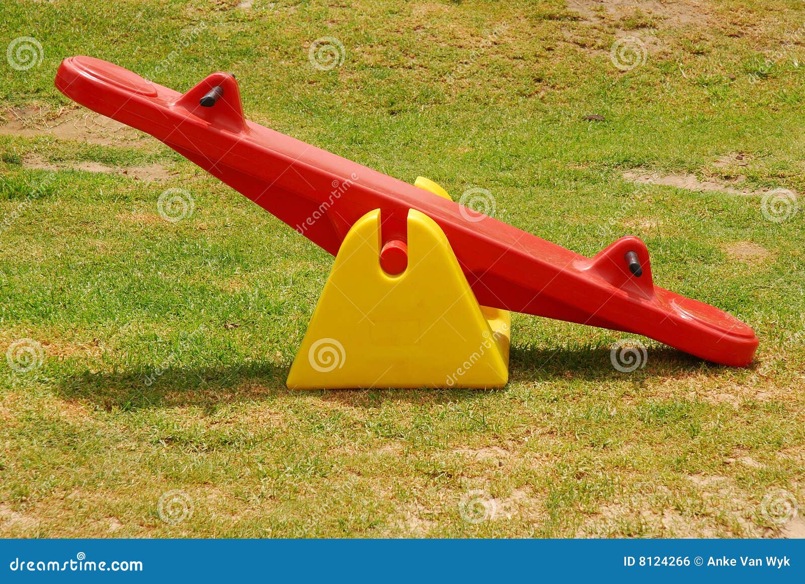 Balançoir en stationnement. Une balançoir en plastique colorée en rouge et jaune pour que les gosses jouent la position sur l'herbe verte en stationnement à l'extérieur en soleil