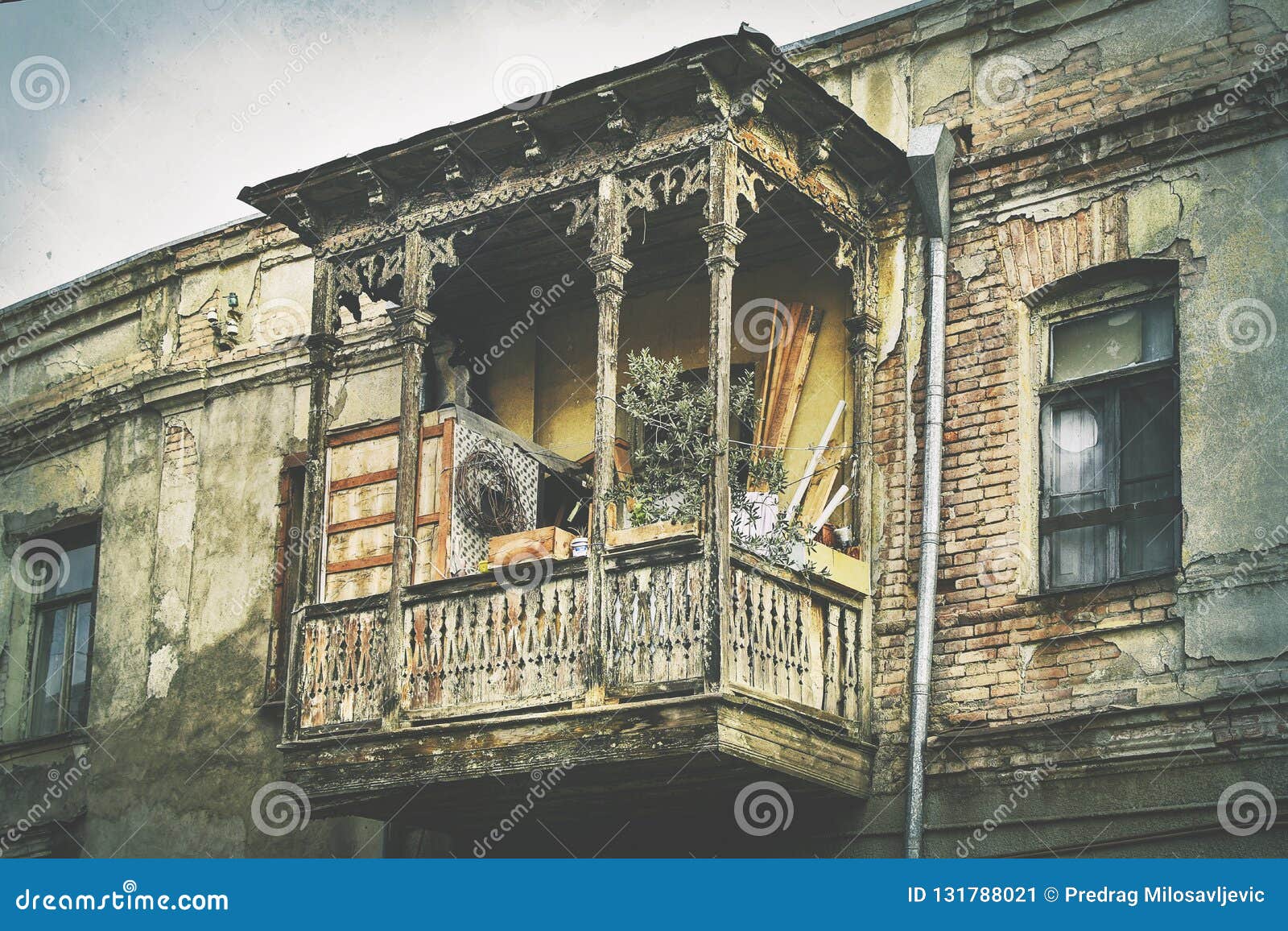 Balcão de madeira da arquitetura Georgian tradicional velha do estilo com as decorações cinzeladas na cidade velha Tbilisi Fachada danificada