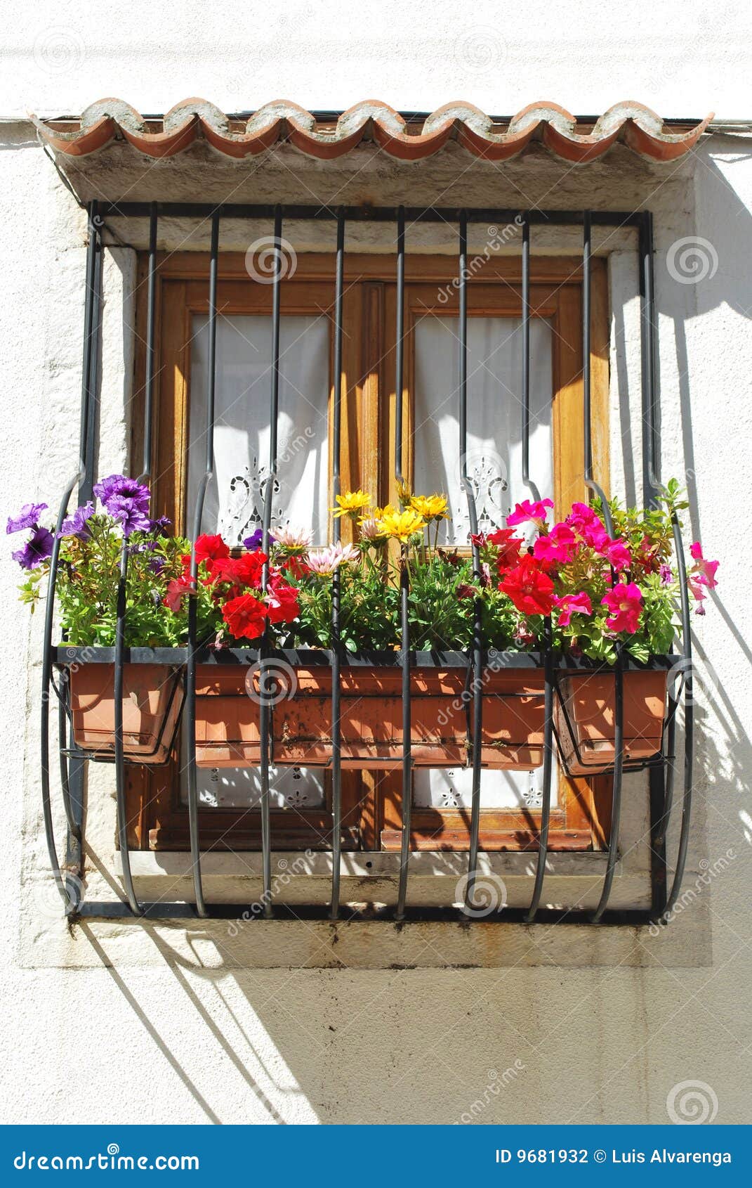 Balcón típico de la ventana con las flores en Lisboa. Balcón hermoso y encantado de un edificio residencial de la ventana con las flores magníficas