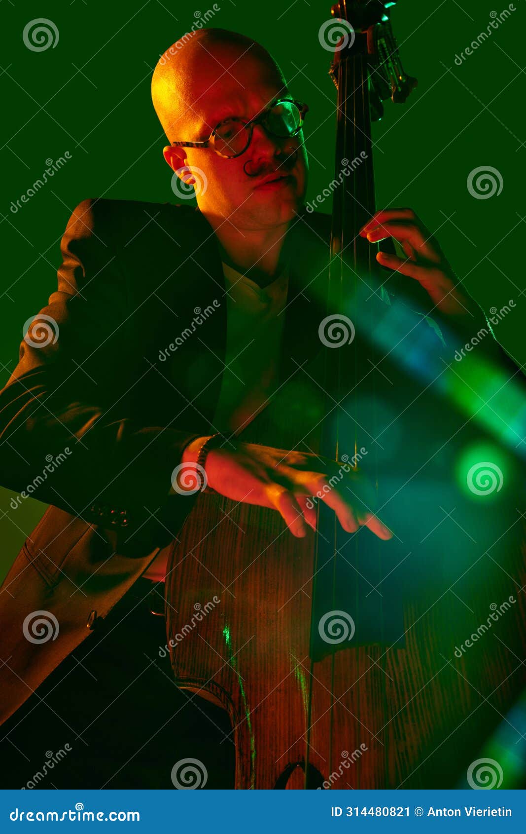 bald man, talented cellist performing jazz compositions in red-green neon light against gradient studio background.