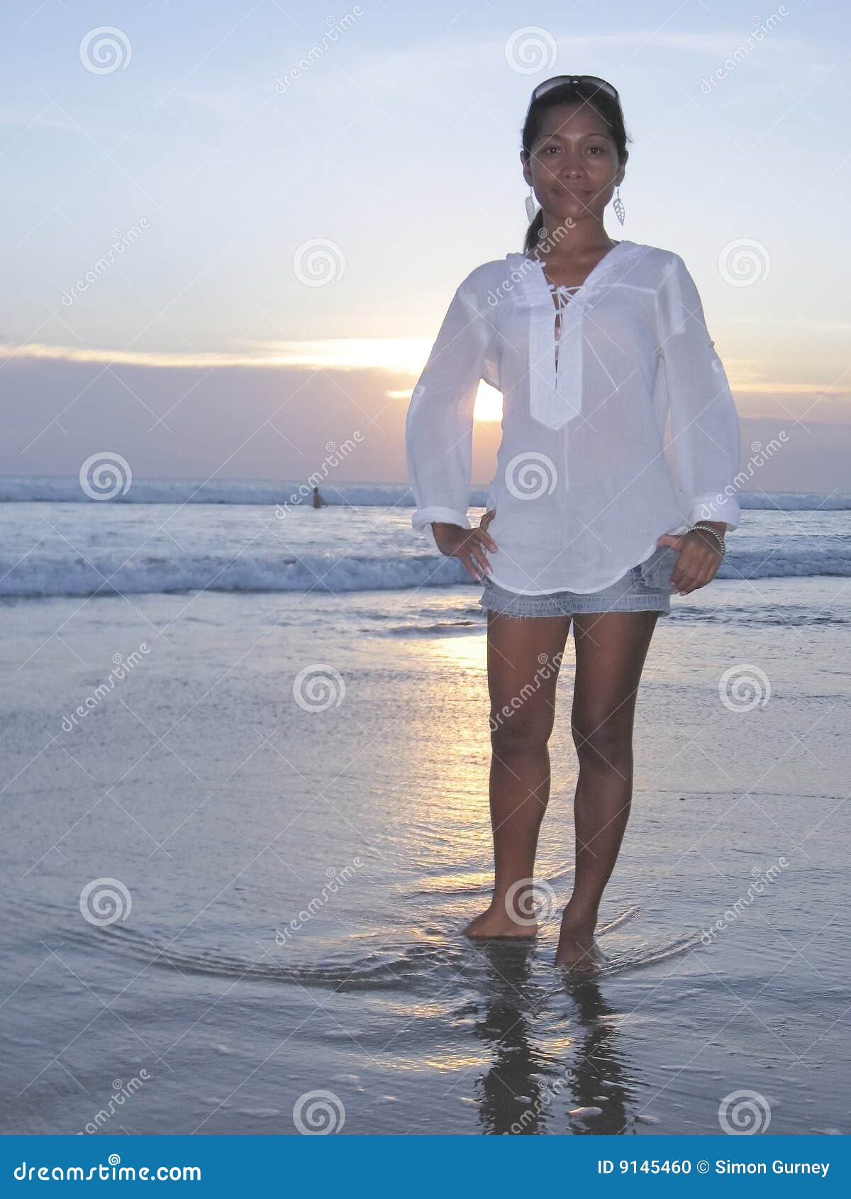 Asian girl on kuta beach bali indonesia at sunset with sun behind 