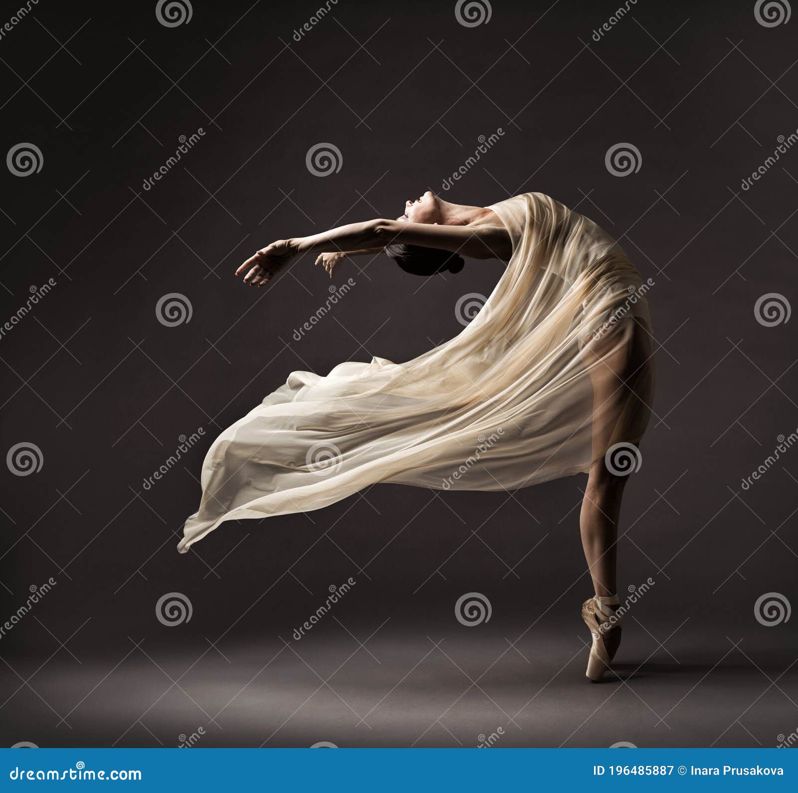 ballerina dancing with silk fabric, modern ballet dancer in fluttering waving cloth, pointe shoes, gray background